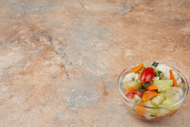 Tasty vegetables on glass plate on marble.