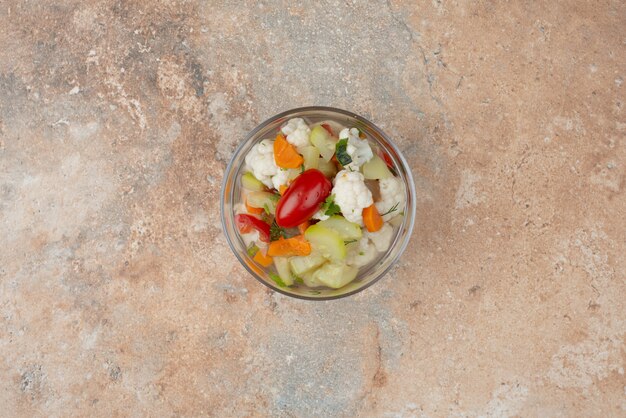 Tasty vegetables on glass plate on marble.