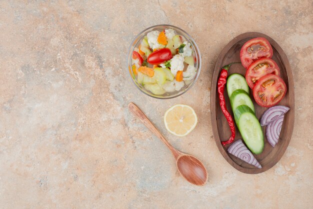 대리석에 토마토, 오이, 양파의 나무 보드와 유리 접시에 맛있는 야채
