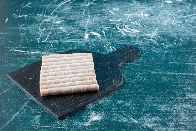 Free photo tasty wafer rolls on black cutting board.