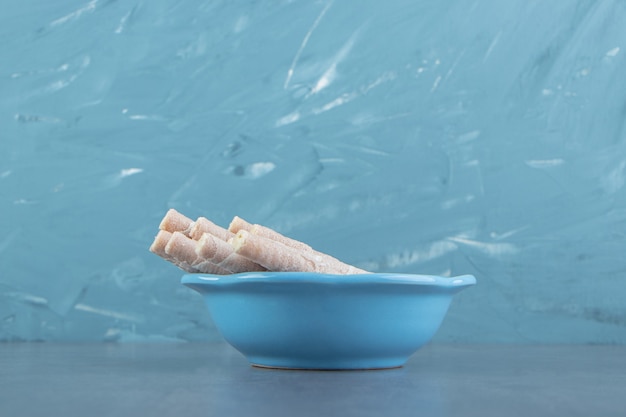 Tasty wafer rolls in blue bowl.