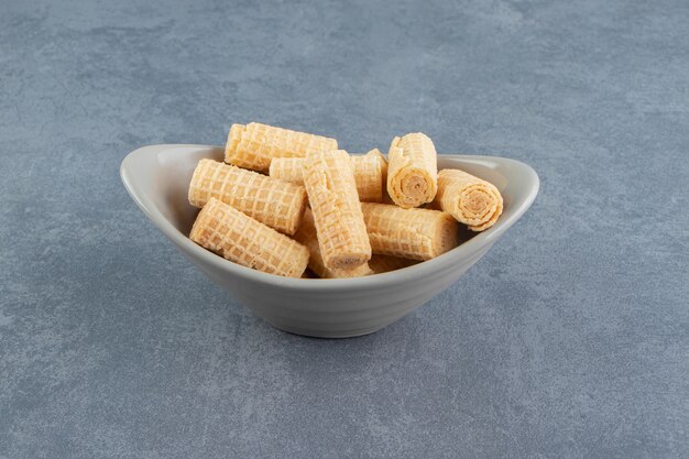 Tasty waffle rolls in ceramic bowl. 