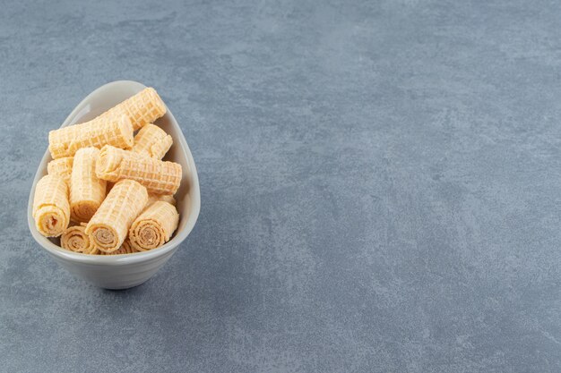 Tasty waffle rolls in ceramic bowl.