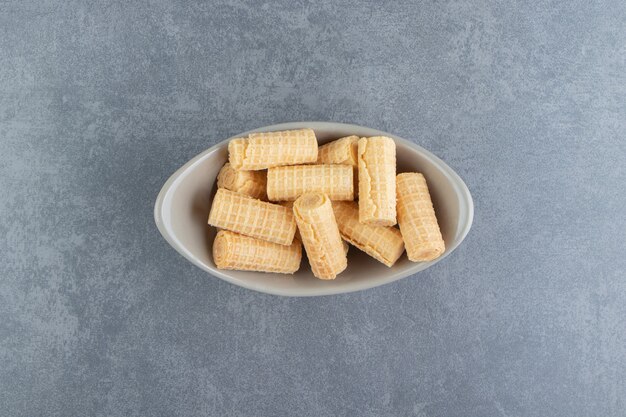 Tasty waffle rolls in ceramic bowl.