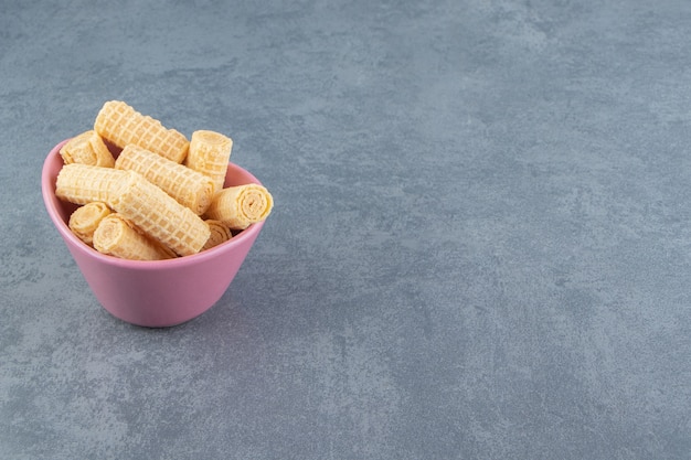 Tasty waffle rolls in pink bowl.