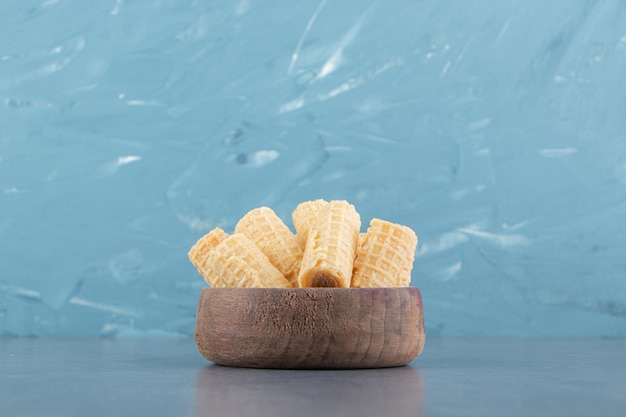 Tasty waffle rolls in wooden bowl.