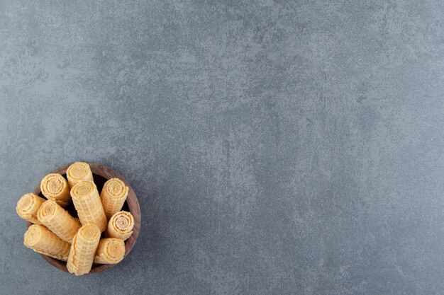 Tasty waffle rolls in wooden bowl.