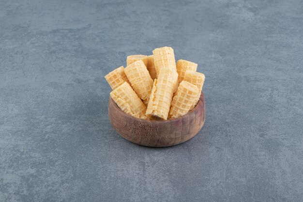 Tasty waffle rolls in wooden bowl.