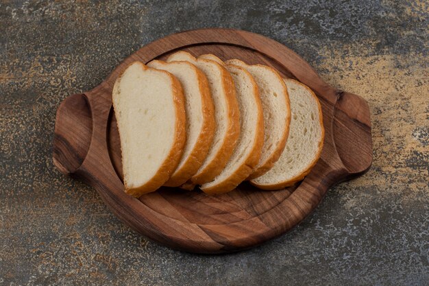 Tasty white bread slices on wooden board