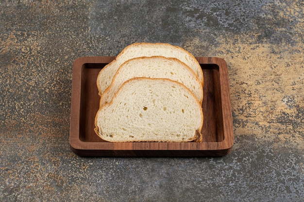 Вкусные кусочки белого хлеба на деревянной тарелке
