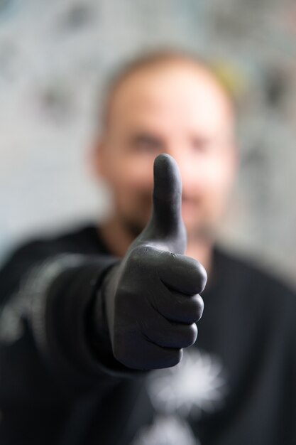 Tattoo artist wearing a black latex gloves showing a thumbs up