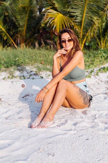 tattooed caucasian woman in denim shorts and green trendy crop top