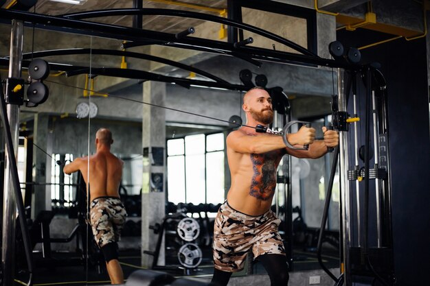 Tattooed fit man doing exercise at the gym