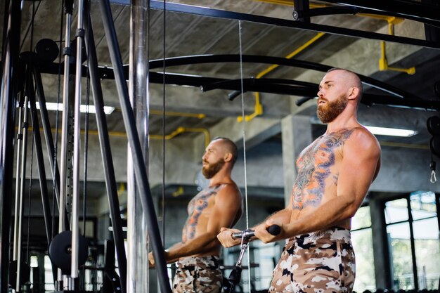 Tattooed fit man doing exercise at the gym