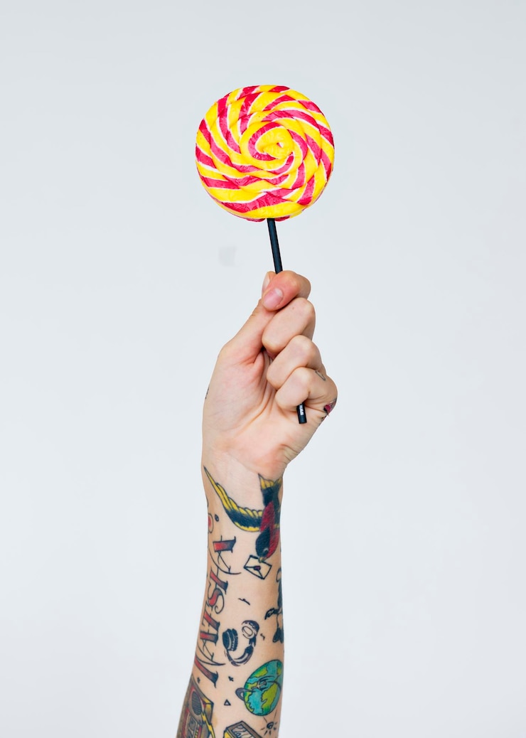 Free Photo tattooed hand showing a lollipop