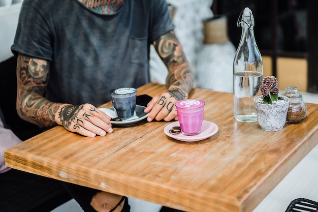 Mani tatuate. mani che tengono un bicchiere con il caffè.