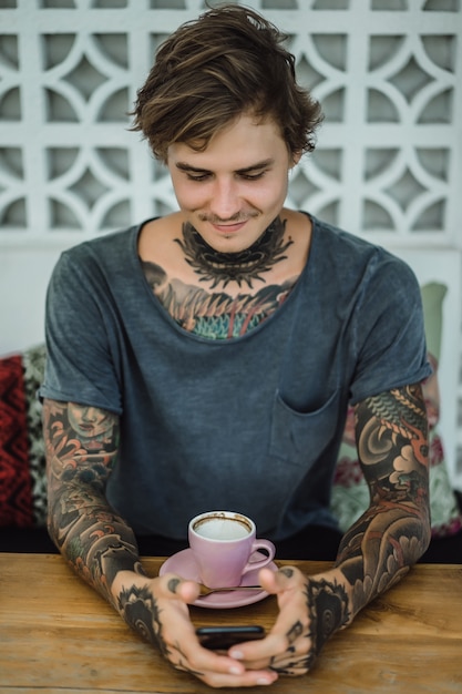 카페에서 커피를 마시는 문신 된 남자