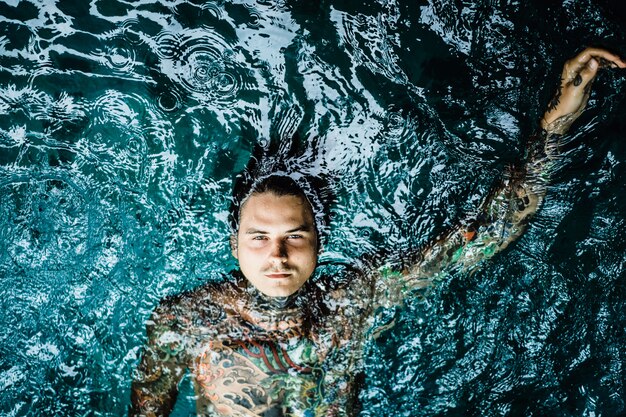 tattooed man in the pool in the rain. 
