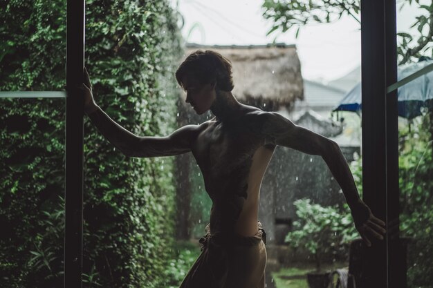 татуированный мужчина, создающий против дождя