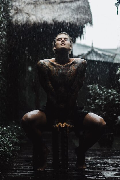 tattooed man posing in the rain