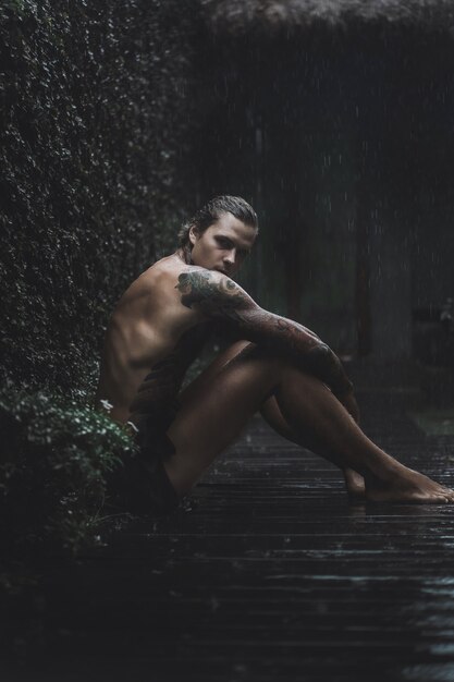 татуированный мужчина позирует в дождь