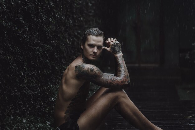 tattooed man posing in the rain