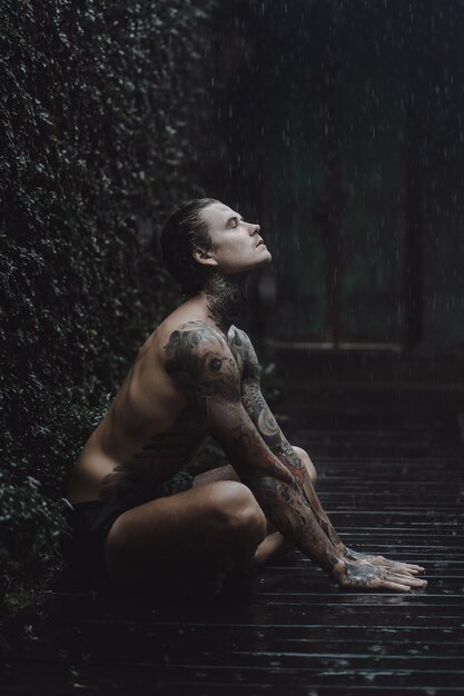 tattooed man posing in the rain