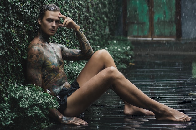 tattooed man posing in the rain