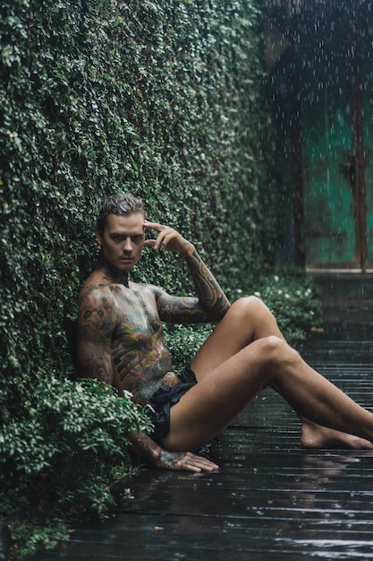 tattooed man posing in the rain