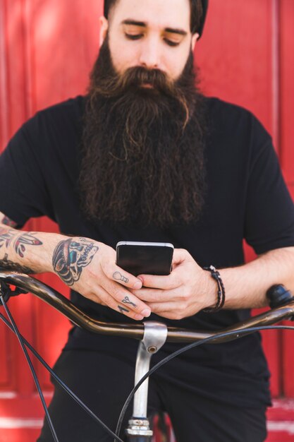 Tattooed man using cellphone sitting on bike