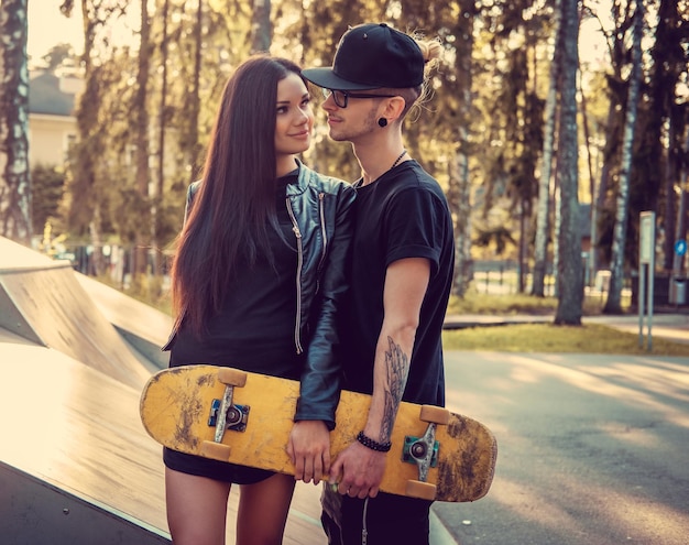 Tattooed skater and his girlfriend in skate park.