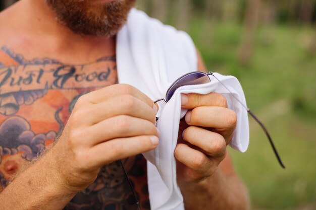 Tattooed strong man on jungle tropical field without shirt