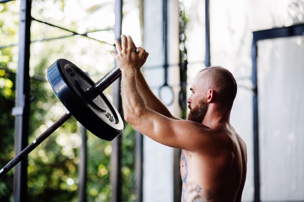 Tattooed strong man with a beard in the gym