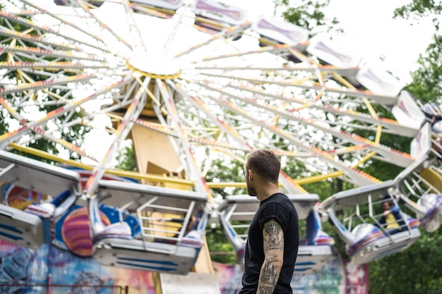 tattooed young man in an amusement park on the background of a merry-go-round