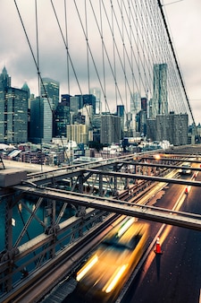 Taxi cab crossing the brooklyn bridge in new york, manhattan skyline in background