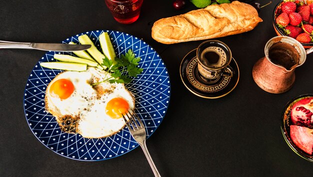 Tea, bread and fried omelette with slices of cucumber on blue plate