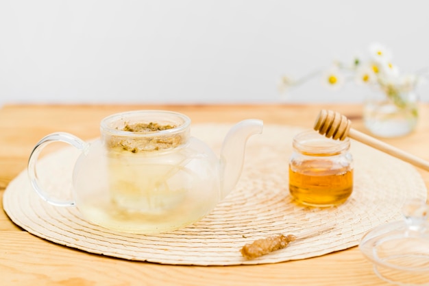 Tea brewing in teapot near honey jar