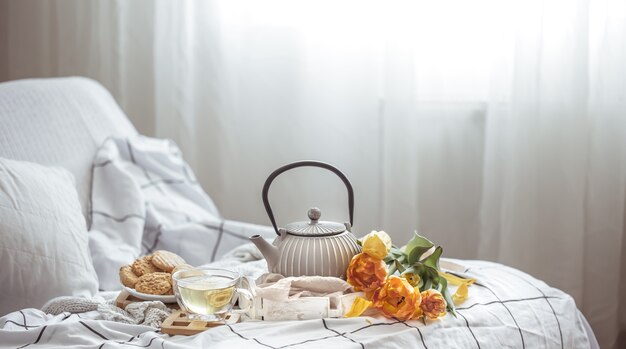 Tea, cookies and a bouquet of fresh tulips in bed. Breakfast and spring morning concept.