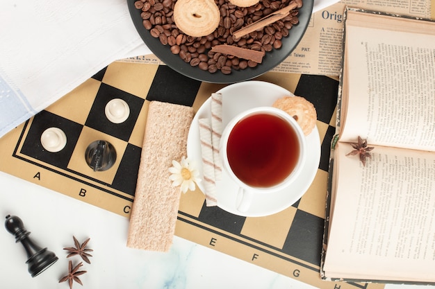 A tea cup and a book on a chessboard