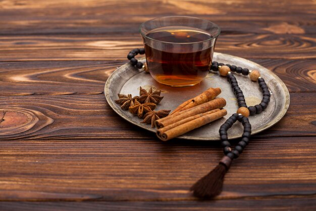 Tea cup with cinnamon and rosary beads on plate