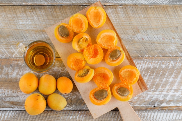 Tea in a glass mug with apricots flat lay on wooden and cutting board