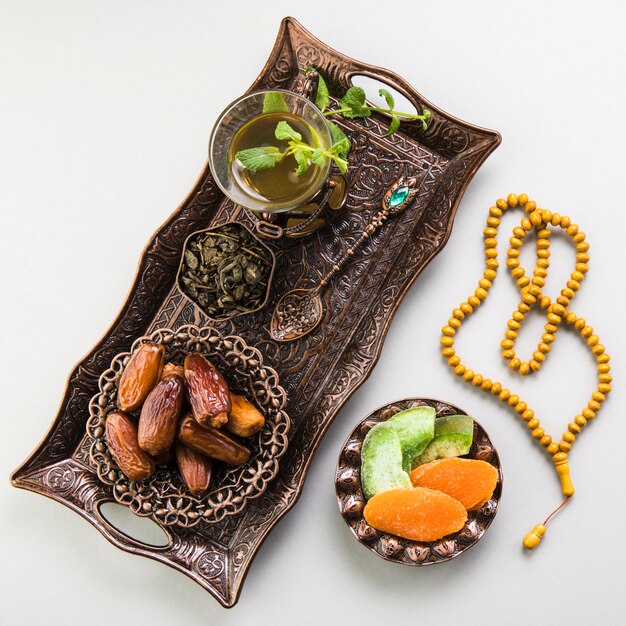 Tea glass with dates fruit and beads on tray