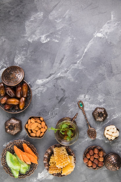 Free photo tea glass with dates fruit and honeycomb on grey table