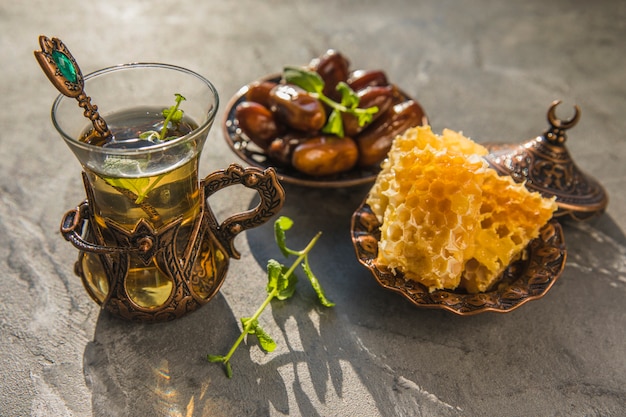 Foto gratuita bicchiere da tè con frutta data e nido d'ape