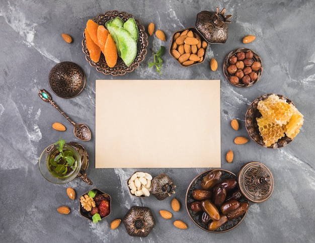 Foto gratuita bicchiere da tè con frutta data, noci e carta bianca