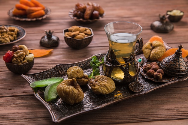 Tea glass with dried figs and nuts on tray 