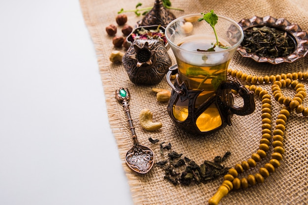 Tea glass with nuts, herbs and beads on canvas