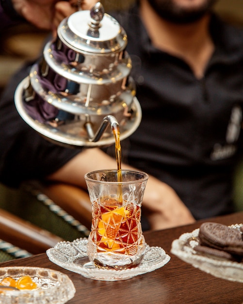 Чай наливают из стального чайника в хрустальное стекло армуду