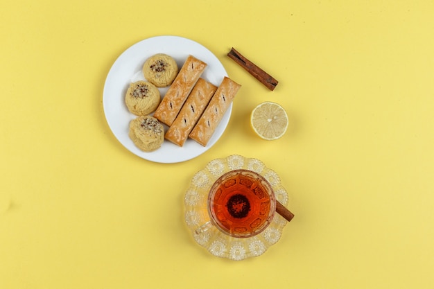 Tea, lemon, cinnamon sticks, and biscuits