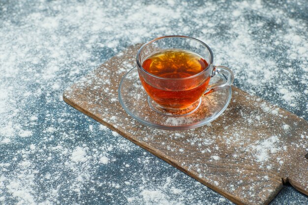 Tea in a mug with sprinkled flour high angle view on concrete and cutting board